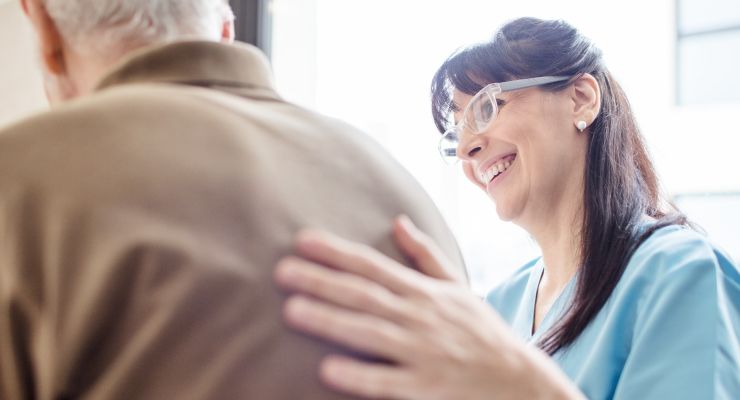 Image of a nurse with her hand on the back of an elderly patient